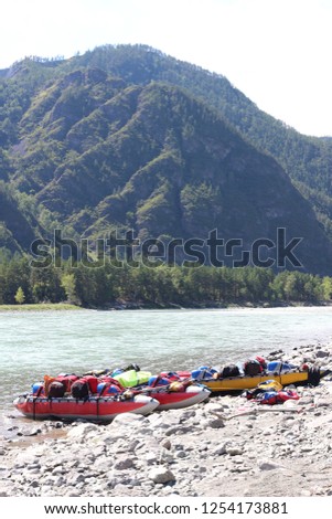 Excellent mountain landscape with the legendary mountain river "Katun" of turquoise color and a sport catamaran moored to the shore. Wonderful view of the mountains and the river. Russia, Altai 
