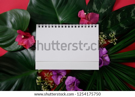 Mock-up white paper with space for text or picture on red background and tropical leaves and flowers