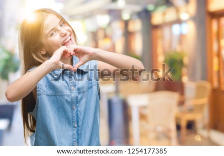 Young beautiful girl over isolated background smiling in love showing heart symbol and shape with hands. Romantic concept.