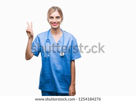 Young beautiful blonde doctor surgeon nurse woman over isolated background showing and pointing up with fingers number two while smiling confident and happy.