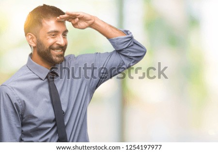 Adult hispanic business man over isolated background very happy and smiling looking far away with hand over head. Searching concept.