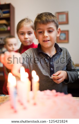 Boy is lighting the birthday cake candles