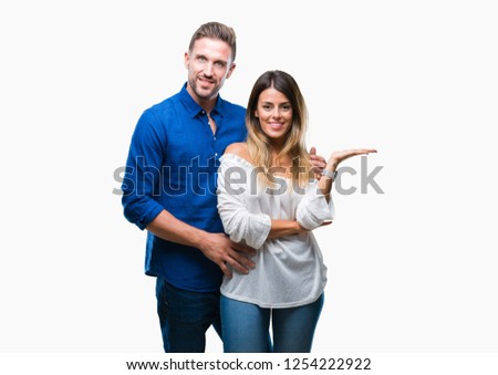 Young couple in love over isolated background smiling cheerful presenting and pointing with palm of hand looking at the camera.