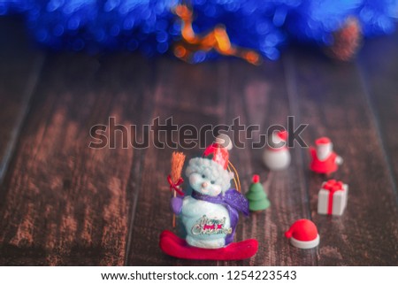 Seasonal rustic Christmas border composed of decorative gifts, nuts and over a wooden background with copyspace, overhead view. Close-up of Snowman in a red cap on wooden table. Christmas decoration.