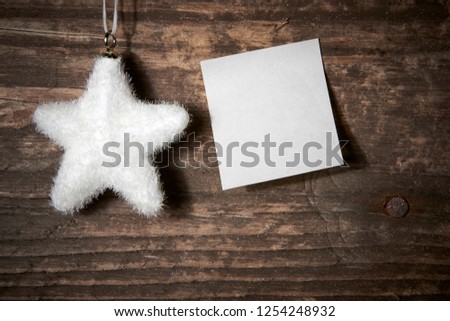 Christmas star of white color as a decoration hanging from a rough wooden board with post-it