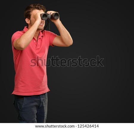 casual man looking into binocular isolated on black background