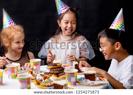 girls are liokking at the funny boy with cream of the cake on his during the holiday. close up photo. isolated black background