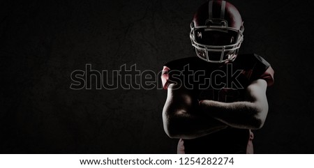 American football player standing with arms crossed against old wall background