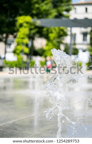 Photograph of a toddler playing in city splash park fountains with focus on the frozen water