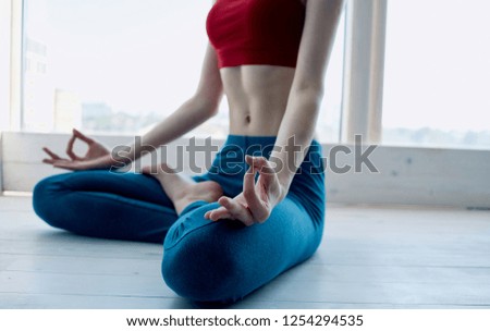 A woman practices yoga near the window                     