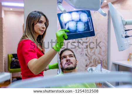 Dentist explaining the details of a x-ray picture to her patient.  Female dentist showing teeth x-ray to patient girl at dental clinic office. Healthcare, medical and dentistry concept.