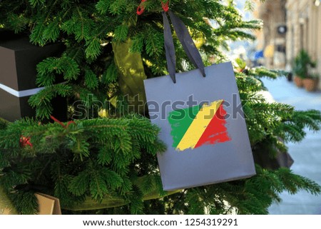 Congo flag printed on a Christmas shopping bag. Close up of a shopping bag as a decoration on a Xmas tree on a street. New Year or Christmas shopping, local market sale and deals concept. 