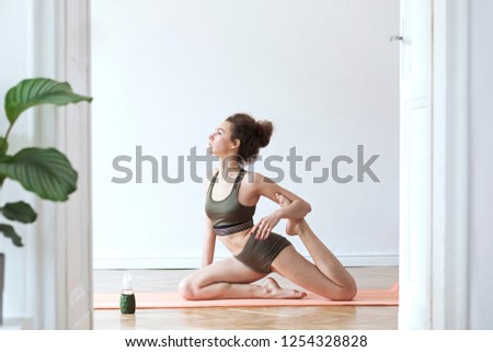 Young darkhair, active woman exercising and stratching on the floor at her studio. Healthy lifestyle, home training, mental balance.