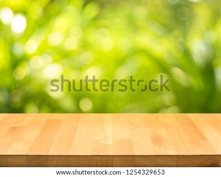 Empty of wood table top on blur of fresh green abstract from garden backgrounds.For montage product display or key visual layout