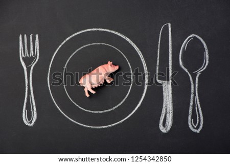 Toy pink pig on a plate in the figure on the chalk board