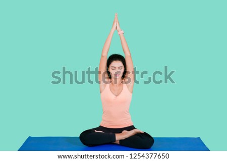 Picture of young woman lifting hands while doing yoga exercise in the studio