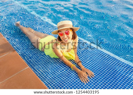 Happy asian Woman in hat nejoying vacation in swimming pool on the roof