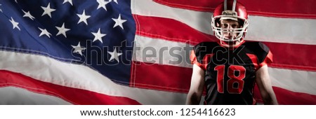 American football player standing in helmet against close-up of an american flag