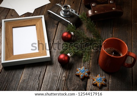 Old photos, frame, camera, pine tree branch and cup of coffee with christmas decorations on wooden background.