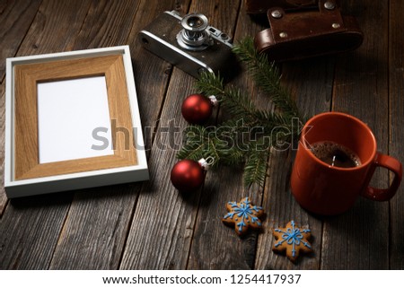 Old photos, frame, camera, pine tree branch and cup of coffee with christmas decorations on wooden background.