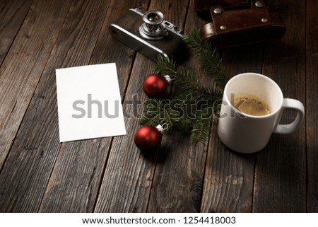 Old photos, camera, pine tree branch and cup of coffee with christmas decorations on wooden background.