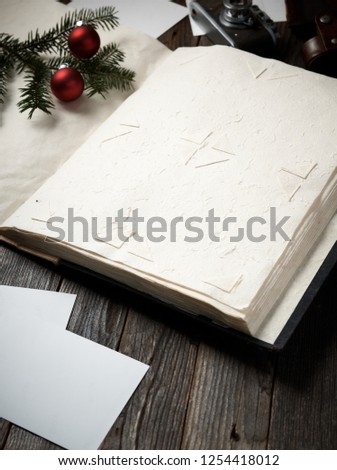 Old photo album, photos, camera and pine tree branch with christmas decorations on wooden background.