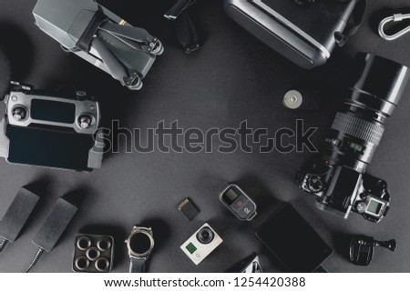 Work space photographer with laptop, digital camera, memory card, action camera, drone, remote controller, phone and camera accessory. Top view on black table background. Concept of mockup template.