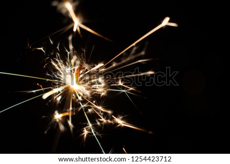 Burning sparkler, abstract blur background. New year card with fireworks and pink forest.