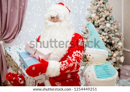 Portrait of Santa Claus with a white beard and gifts in his hands close-up in the New Year's festive interior