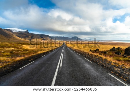 Deserted Straight Road through Lava Fields and Volcanic Mountains in Iceland on a Sunny Autumn Day. The Coast and the Sea are Visible on the Right Side of the Picture