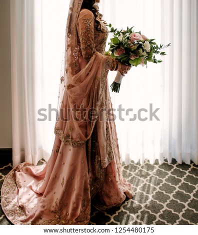 Pakistani Indian bride holding the bouquet and wearing wedding Lehnga skirts dress Royalty-Free Stock Photo #1254480175
