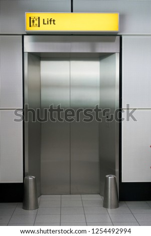 Closed elevator with stainless brushed steel doors and an illuminated life sign above the doors.