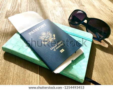 Cover of The United States of America with tickets, travel journal and sunglasses on a wooden table