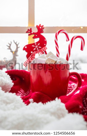 Red cup with hot chocolate marshmallows on white window blanket, christmas composition
