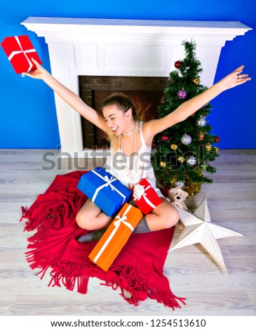 New year holiday picture of happy woman enjoying her presents, posing at cozy room with Christmas tree.