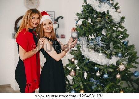 In a beautiful decorated room with a Christmas tree is standing a two young girs 