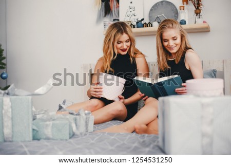 In a beautiful decorated room with a Christmas tree is sitting a two young girls with presents