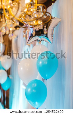 Baby-boy birthday party decor. White and blue balloons, lights and large Teddy-bear decorate restaurant hall ready for festive dinner