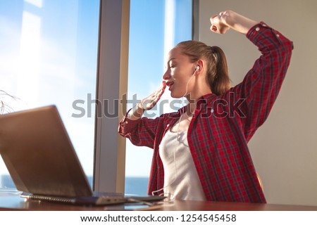 The begining of the work day. Young businesswoman yawning in the workplace. The beginning of the working week after the weekend