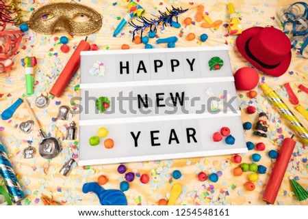 Happy New Year greetings on a lightbox with party dekoration