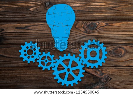 gears, light bulb made of wooden puzzles on a wooden table background. creativity, movement, the business idea.