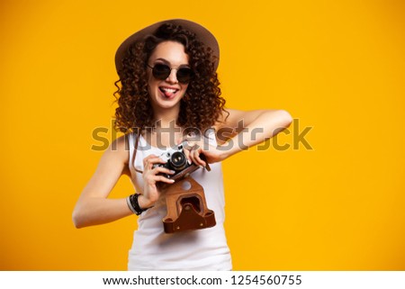 Portrait of laughing young woman in eyeglasses taking pictures on retro vintage photo camera isolated on bright yellow background. People sincere emotions, lifestyle concept. Advertising area