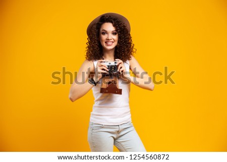 Portrait of laughing young woman taking pictures on retro vintage photo camera isolated on bright yellow background. People sincere emotions, lifestyle concept. Advertising area