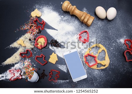 make ginger snaps cookies for christmas. concept of festive. Ingredients for homemade ginger cookies laid out in form of a Christmas tree. symbol of new 2018 Smartphone with a blank screen mock up.