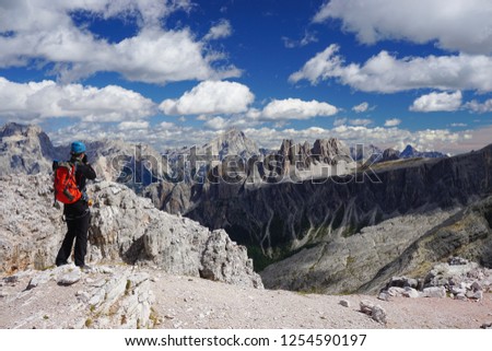 Young climber taking pictures of amazing view on top of Averau peak in the Dolomites (Italy) on a sunny day of summer