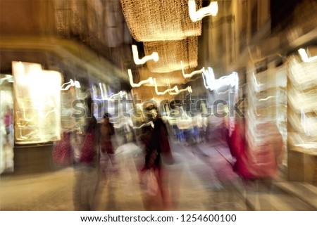 Tribute to Monet, impressionist photograph of the people in a commercial street in Toledo, Spain, photographic sweeps at low shutter speed, Christmas night illumination, illuminated showcase,  