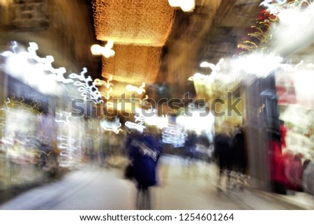 Tribute to Monet, impressionist photograph of the people in a commercial street in Toledo, Spain, photographic sweeps at low shutter speed, Christmas night illumination, illuminated showcase,  