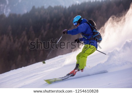 young athlete freestyle Skier having fun while running downhill in beautiful Alpine landscape on sunny day during winter season