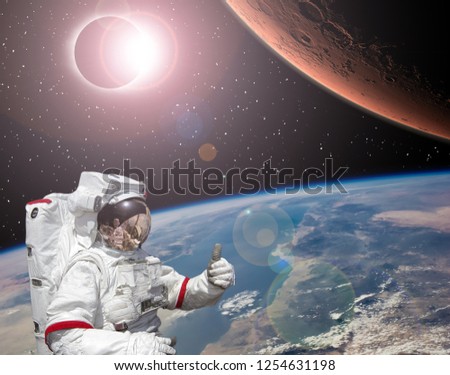 Rocket flies from earth to Mars. Astronaut shows the thumbs-up. Solar eclipse.  The elements of this image furnished by NASA.
