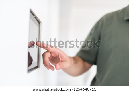 smart home and technology concept close up of male hands pointing finger to tablet pc computer integrated in house indoor wall